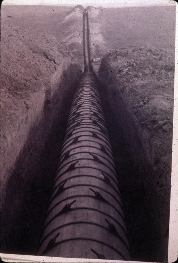 Pipeline built in 1906 to pump water from East Whittier, Calif. to La Habra, Calif. The water originated in artesian wells on the San Gabriel River near Basset, and then flowed to East Whittier by flume and conduit. Photograph appears to have been taken when pipeline was freshly laid, in 1906.